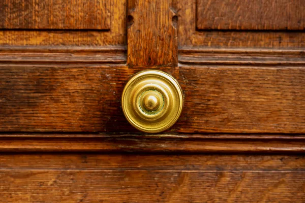 Старая круглая дверная ручка на старой деревянной коричневой двери. Закрыть Париж, Францию. Золотая латунь детали на старой деревянной двери. Ручка на коричневой старой деревянной потрепанной винтажной двери. — стоковое фото