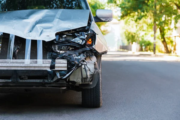 Voiture détruite dans un accident de la route sur la route de la ville. Phare avant cassé cassé, capot bosselé sans pare-chocs sur accident de voiture gris avec espace de copie. Assurance auto vie et maladie. — Photo