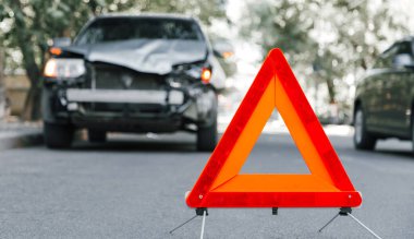 Trafik kazası mahallinde kırmızı acil durum üçgeni işareti. Trafik kazasında yolda kırılmış bir SUV arabası. Çarpışmadan sonra şehir yolundaki trafik kazası. Uzun web pankartı