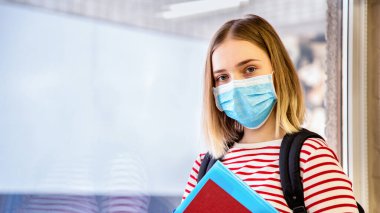 Koruyucu tıp maskeli kız öğrenci. Coronavirus covid tecrit sırasında üniversitenin penceresinin yanındaki sarışın kız öğrencinin portresi. Kopyalama alanı olan uzun web pankartı