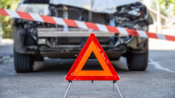 Voiture détruite dans un accident de voiture accident de la route sur la route de la ville avec ruban adhésif de la police et panneau triangle d'arrêt d'urgence rouge. Une voiture cassée brisée. Assurance auto vie et maladie — Photo