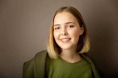 Koyu gri arka planda gülümseyen çekici bir kadın. Mutlu Kafkasyalı Genç Kız. Kopya alanı olan sarı saç portresi.