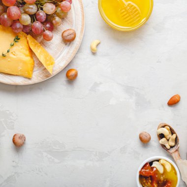 Açık gri kırsal beton arka planda şarap kompozisyonu. Çerçevesi pembe şarap şişesi peynir ve üzüm balı. Camembert peyniri, romantik yemek için şarap barı atıştırmalıkları. Boşluğu kopyala