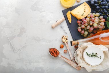 Gül şarabı, peynir, fındık, pembe ve siyah üzümler tahtada ve bal. Camembert peyniri, şarap barı atıştırmalıkları. Fotokopi alanı olan açık gri kırsal beton zemin üzerine şarap bileşimi