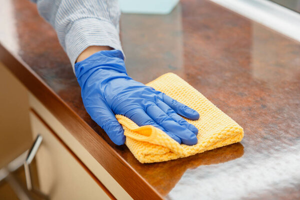 Woman wiping table countertop in kitchen by wet cloth rag. Female charwoman hand cleaning disinfect office home restaurant surfaces.
