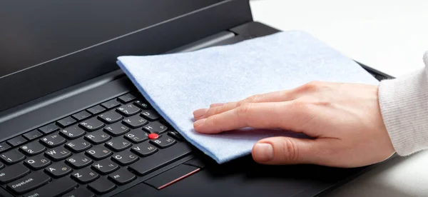 Female hands disinfecting laptop keyboard using wet disinfectant wipes. Woman cleaning keyboard. New Normal cleaning laptop work home surfaces. Long web banner