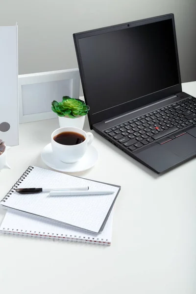 Белый стол с ноутбуком для удаленной работы или учебы. Черный ноутбук с блондинкой раскладкой дисплея на заднем плане. Рабочее место офисного компьютера в домашнем интерьере. — стоковое фото