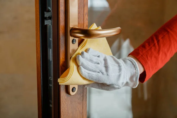 Vrouw Huishoudster in witte handschoenen schoon Deur knop door doek doek. Nieuwe normale Covid 19 coronavirus in oppervlakken desinfectie. Reiniging van de voordeur handvat door antibacteriële alcohol wasmiddel. — Stockfoto