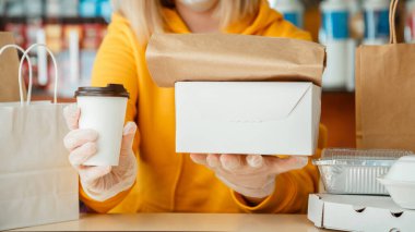 Eldivenli kadın paket servis siparişleriyle çalışıyor. Garson dışarıdan yemek ısmarlarken şehir merkezi 19, koronavirüs kapanıyor. Hazır yemek, hazır pizza, kahve, yemek servisi. Uzun web pankartı.