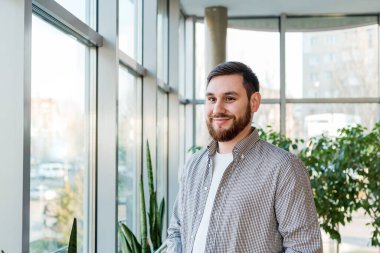 Modern ofisin uzun penceresinin yanında dikilen başarılı sakallı genç adam. Beyaz, yakışıklı, zeki bir işadamı. Açık alanda birlikte çalışma konusunda serbest çalışan