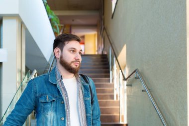 Merdivenlerdeki yakışıklı sakallı adamın portresi. Kafkas işadamı ya da öğrenci merdivenlerde. Boşluğu kopyala.