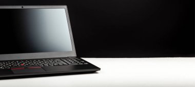 Beyaz masa üzerinde boş ekran şablonu olan siyah dizüstü bilgisayar. Ofis masası çalışma alanı. Uzaktan çalışma ya da çalışma için dizüstü bilgisayar. Minimalist tasarım. Kopyalama alanı olan uzun web pankartı.