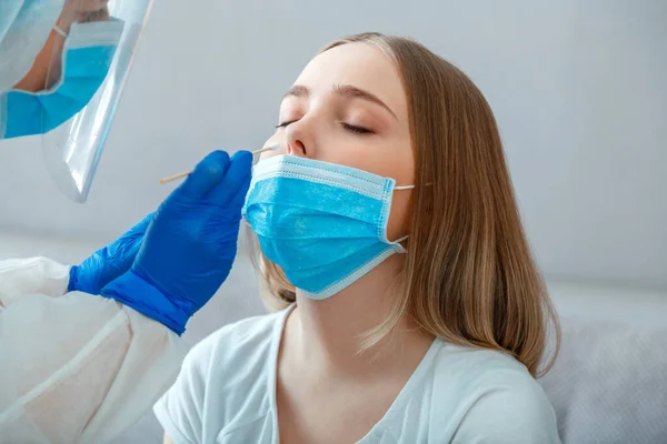 Doktor kadın hastaya PCR testi yapar. Hemşire, Coronavirus covid 19 'u kontrol etmek için tükürük örneği aldı. Koruyucu maske takan sağlık çalışanı evde ya da klinikte PCR testi yapıyor..
