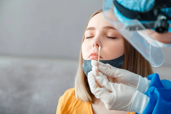 Coronavirüs kovid 19 hastalarının teşhisi. Koruyucu tıbbi maskeli doktor nazofaringeal kültürü kadınlara test ediyor. Hemşire pamuklu çubukla burun testine giriyor. Boşluğu kopyala.