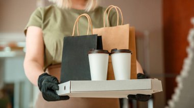 Garson dışarıdan yemek ısmarlarken şehir hapishanesi 19 kilitleniyor. Koruyucu maske ve eldiven takmış tanınmayan kadın garson paket servis siparişleriyle çalışıyor. Pizza ve kahve teslimatı. Uzun web pankartı.