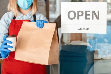 Ön kapıdaki kilit kapandıktan sonra Kapı Kapısı Açık 'ı tekrar açıyorum. Yeni normalleri yeniden aç. Koruyucu tıbbi maskeli ve eldivenli kadın garson paket servis siparişi veriyor. Yemek siparişi.