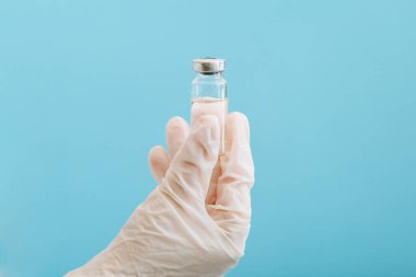 Cam şişe içinde Covid 19 aşı, doktor elinde ilaç sıvısı. Aşı aşıları mavi arka planda tedavi olarak kullanılıyor. Covid 19 Sağlık Hizmetleri Tıbbi Bağışıklık Konsepti