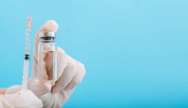 Şişe ve şırıngada Covid 19 aşı, doktor elinde ilaç sıvısı. Aşı enjeksiyonları mavi üzerinde tedavi olarak kullanılıyor. Covid 19 Sağlık Hizmetleri Tıbbi Bağışıklık Konsepti. Kopyalama alanı olan uzun web pankartı