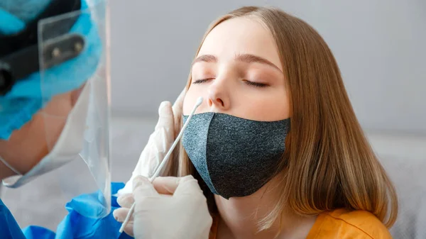 Doctor in protective medical mask taking PCR test nasopharyngeal culture to woman. Diagnostics testing patients coronavirus covid 19.Nurse take saliva sample test through nose with cotton swab Banner.