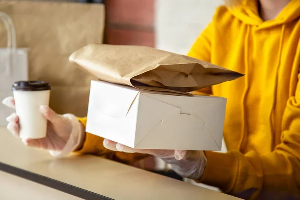 Eldivenli kadın paket servis siparişleriyle çalışıyor. Garson dışarıdan yemek ısmarlarken şehir merkezi 19, koronavirüs kapanıyor. Hazır yemek, hazır pizza, kahve, yemek servisi.