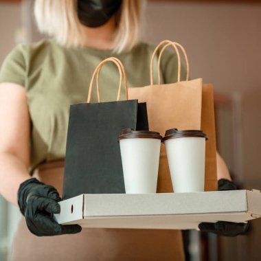 Garson dışarıdan yemek ısmarlarken şehir hapishanesi 19 kilitleniyor. Koruyucu maske ve eldiven takmış tanınmayan kadın garson paket servis siparişleriyle çalışıyor. Pizza ve kahve teslimatı. Kare mahsul.