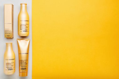 L 'oreal Profesnel Paris Serie Expert loreal besleyici saç ürünleri seti. Sarı arka planda Loreal saç şampuanı maskesi. Altın kozmetik şişeleri. Düz metin kopyalama alanı.