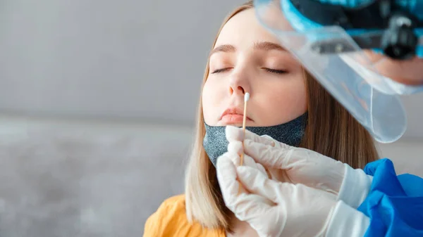 Coronavirüs kovid 19 hastalarının teşhisi. Koruyucu tıbbi maskeli doktor nazofaringeal kültürü kadınlara test ediyor. Hemşire pamuklu çubukla burun testine giriyor. Sancak kopyalama alanı.