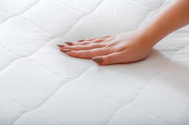 Female hand Pressing Testing mattress to Check softness. Choice comfortable mattress for sleep in store. quality control hardness of mattress materials Orthopedic Foam. Woman choosing new mattress. clipart