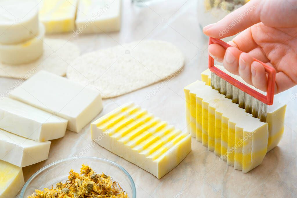 Diy soap cutting process. Craft soap making process with herbs and flowers. hobby eco artisan handmade soap on white table. Many various white yellow homemade bar soaps
