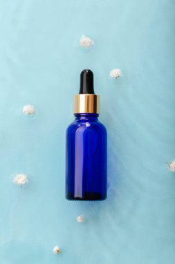 Mavi su yüzeyinde çiçekli damlalar serumu kozmetik ürünleri. Cilt bakımı nem dengesi için yüz estetiği. Aqua kolajen düşürücü veya hyaluron serumu