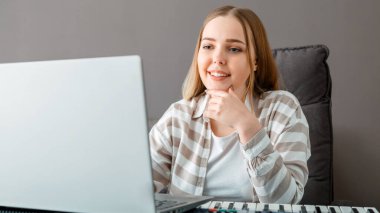 Kadın, evde dizüstü bilgisayar kullanarak öğretmeniyle video üzerinden piyano çalmayı öğreniyor. Online ders sırasında kadın sentezleyici piyano çalıyor. Çevrimiçi konser sanatçısı. Uzun web pankartı.