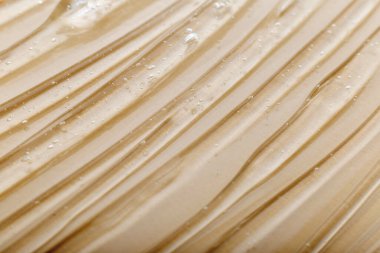 Bej rengi açık renk arka planda kozmetik nemlendirici ürünün berrak sulu jel dokusu. Hyaluronik asit jeli ya da açık ten renginde kolajen arkaplan dokusu. Su yüzeyi, nemlendirici serum.