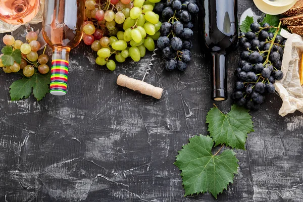 ボトルチーズに赤ワイン、濃いコンクリートの背景にブドウの植物と白ピンクと黒のブドウをバラ。さまざまな種類のワインとブドウ品種を盛り合わせます。飲食物 — ストック写真