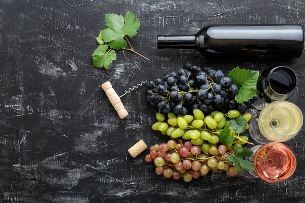 さまざまな種類のワインとグレードの品種を品揃えします。テイスティングホワイトピンクと黒ブドウの近くのガラスで赤ワインをバラ,濃いコンクリートの背景に赤ワインボトル — ストック写真