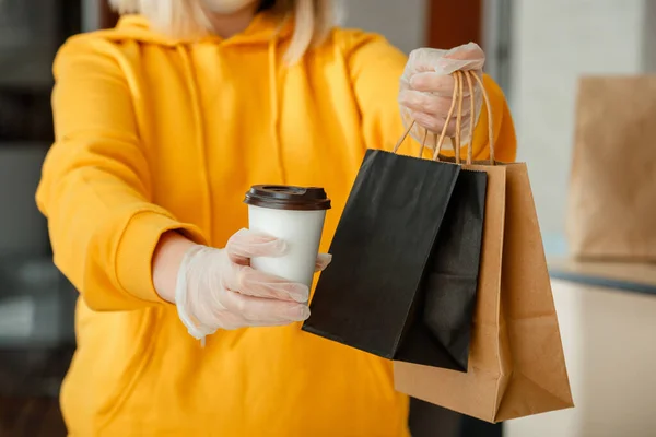 Takeaway food paper bag, cup of coffee or drink. Food bag lunch mock up package to go in takeaway restaurant. Kitchen worker issues online orders in gloves. Contactless food delivery