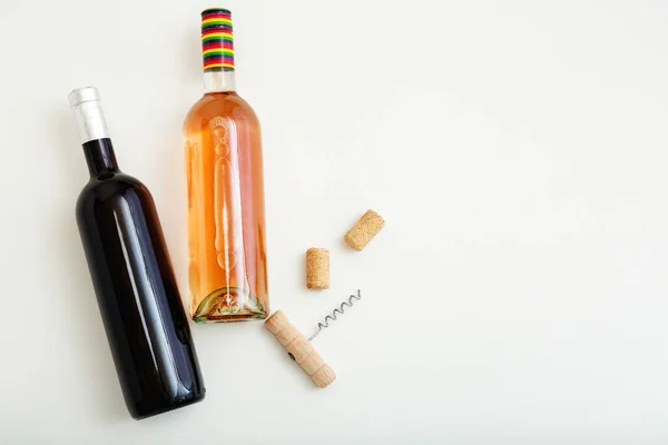 Rozenwijnfles en rode wijnfles kurkentrekker en kurk. Minimalistische wijn compositie bovenaanzicht op witte achtergrond. Twee flessen wijn merk mockup. Vlakke lay met kopieerruimte. — Stockfoto