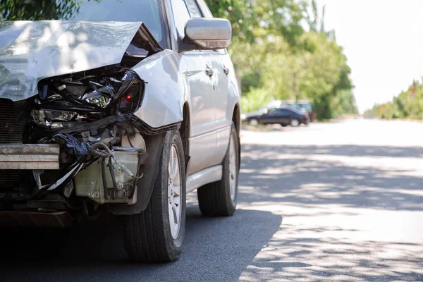 Destruido coche en accidente de tráfico accidente de coche en la carretera de la ciudad con espacio de copia en la carretera de la ciudad. Faro delantero roto destrozado, capucha abollada sin parachoques en accidente de coche. Auto vida y seguro de salud. — Foto de Stock