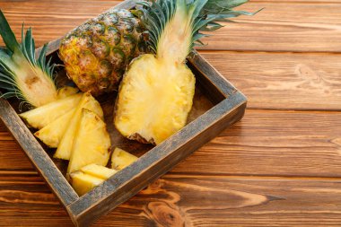 Dilimlenmiş Ananas. Bromelain tropikal yaz meyveli ananas yarımları ve tüm ananas kahverengi siyah masa üzerinde tahta kutuda fotokopi alanı ile birlikte