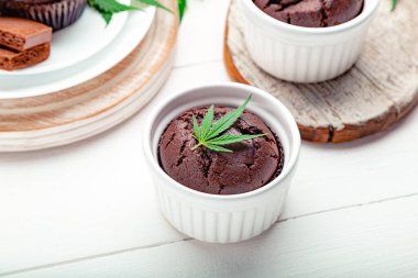 Kenevirli çikolatalı çörekler ot CD 'si bırakır. Tıbbi marihuana, tatlı olarak kenevir ilacı. Ahşap beyaz masada marihuana ile ot keki pişirmek.