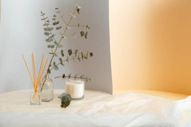 Okaliptüs dalları vazoda buket ve Aromatik ev parfümü çubukları, oda parfümü mumu. Gri sarı ve buruşuk kağıt zemin üzerinde kopya alanı olan ev içi konfor elementi ve aromaterapisi