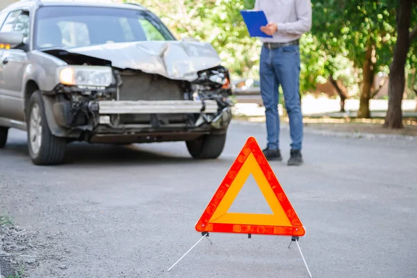 A férfi biztosítási ügynök leírja a balesetet követő autóbalesetet. Autóbiztosítás úton. Egy ember táblagéppel méri a balesetet. Közúti törött autó. — Stock Fotó