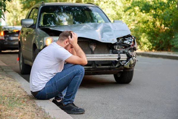 Car accident. Man holding his head after car accident. Man regrets damage caused during car wreck. Man driver is indignant had an accident on road. Headache injury blow to head. — Stock Photo, Image