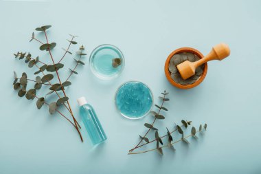 Doğal kozmetik ürünleri, okaliptüs otları ve ahşap havan. Okaliptüs Gel Serum Doğal Kozmetik Şişe yaprakları ve okaliptüs dallarıyla. Cilt kozmetik ilaçlarında okaliptüs yağı