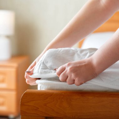 Kadın şiltenin köşesinde yeni bir yastık takıyor. Evde ya da otelde çarşaf. Çarşaf yumuşak, temiz beyaz bir şilteye takılır. Yatak odasının iç tarafındaki kirli ve yıkanmış çarşaflardan korunmak için.