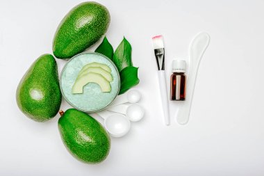 Cilt bakımı ürünleri avokado meyvesinden doğal organik kozmetik ürünleri, beyaz arka planda gerekli yağ. Avokado vücut fırçası ya da yüz maskesi, avokadodan ev yapımı banyo güzellik ürünleri.