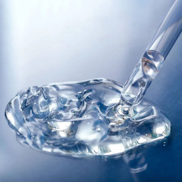 Swatch de soro gel transparente líquido com pipeta em fundo de vidro de cor azul. Produto cosmético para cuidados com a pele ou gel líquido claro médico. Praça Fechar — Fotografia de Stock