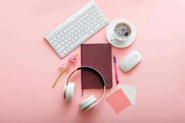 Ofis malzemeleri pembe masa çalışma masasında. Klavye fare kulaklığı ve kahve çiçekli kız çalışma alanı. Liseli kız işyeri. Okula Dönüş Konsepti.