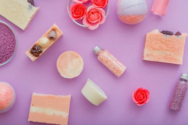 Mor arka planda el yapımı pembe renkli sabun spa ürünleri deseni. Bomba boncukları banyo tozu. Vücut spa cilt bakımı cilt bakımı için banyo ürünleri. Aromaterapi gülleri. Düz yatıyordu