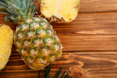 Olgun Ananas. Tropikal yaz meyveli ananas dilimi ve tüm ananası tahtadan kahverengi bir masada. Kopyalama alanı olan düz