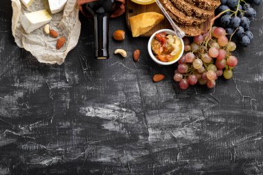 Yiyecek çerezleri koyu beton arka planda farklı peynirler içerir. Şarap ve peynir kompozisyonu. Akdeniz mutfağı yiyeceği gastronomi aperatifi. Boşluğu karatahtaya kopyala